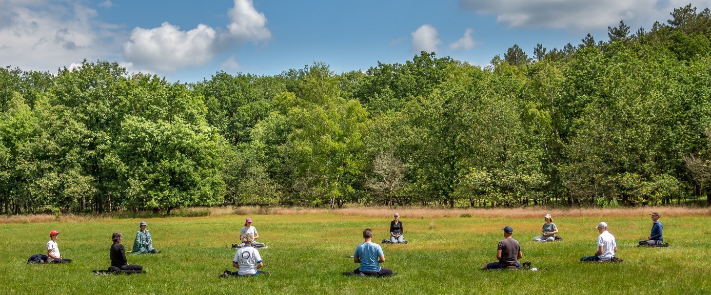 mensen mediteren in een cirkel op het gras op landgoed Den Treek in Lunteren