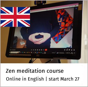 op een monitor toont de zenmeester een mudra, links is een Engelse vlag te zien