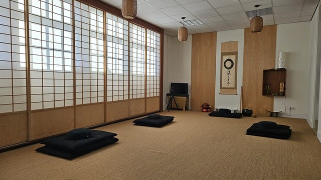 zendo van Zen.nl Delft, een rustig ingerichte ruimte met natuurtinten, meditatiematten, papieren schermen en een scroll met enso